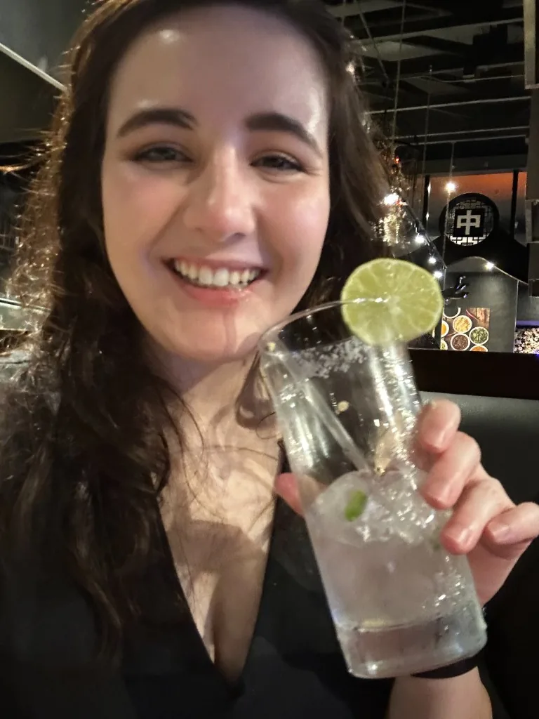 A CI Web Group teammate smiling and holding up a salted-rim glass with a lime wheel