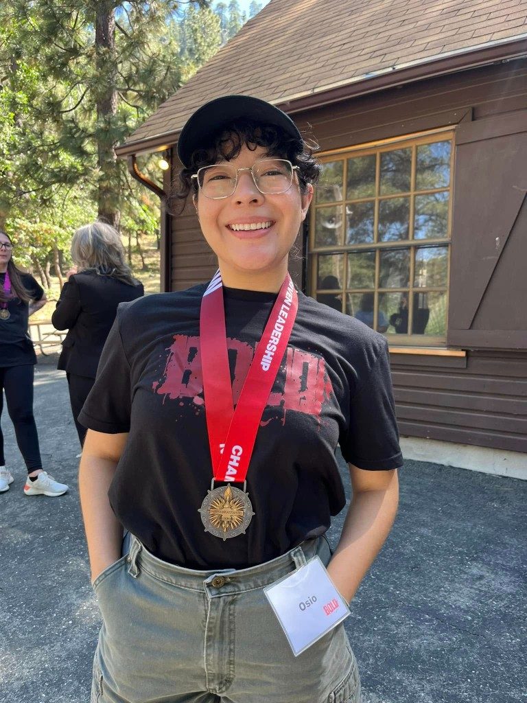 BOLD graduate in a black BOLD shirt wearing a medal