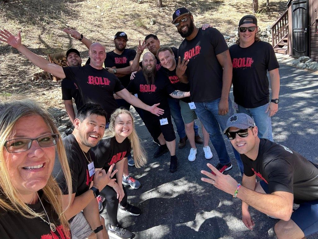 BOLD graduates in black BOLD shirts taking a group selfie