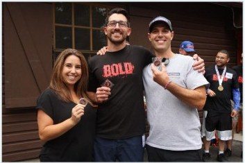 BOLD friends holding medals and coins in front of the cabin