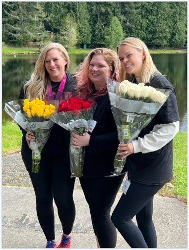 BOLD graduates celebrating with flowers by the lake