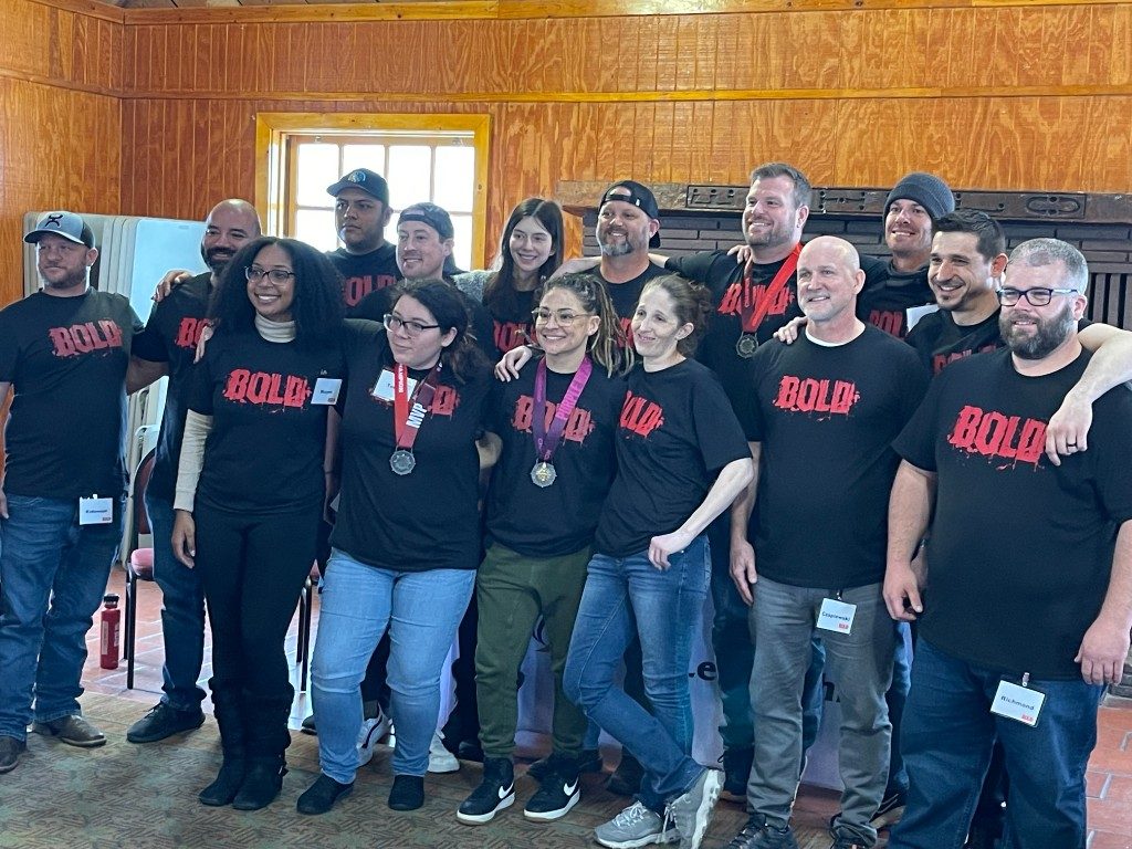 BOLD graduates in matching black BOLD shirts inside a cabin venue