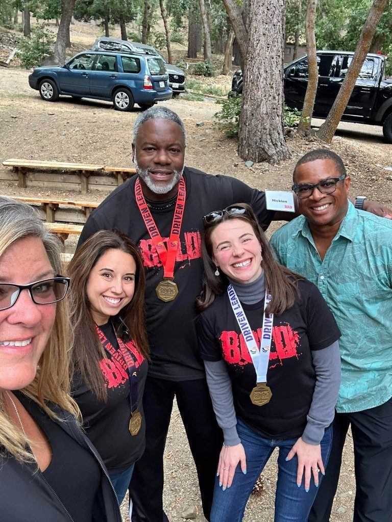 BOLD graduates in black BOLD shirts taking a medal group selfie