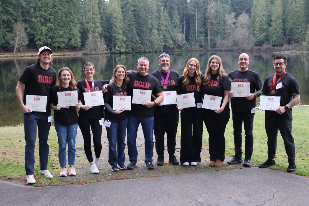 CI Web Group team holding BOLD Advanced Leadership graduation certificates by a lake