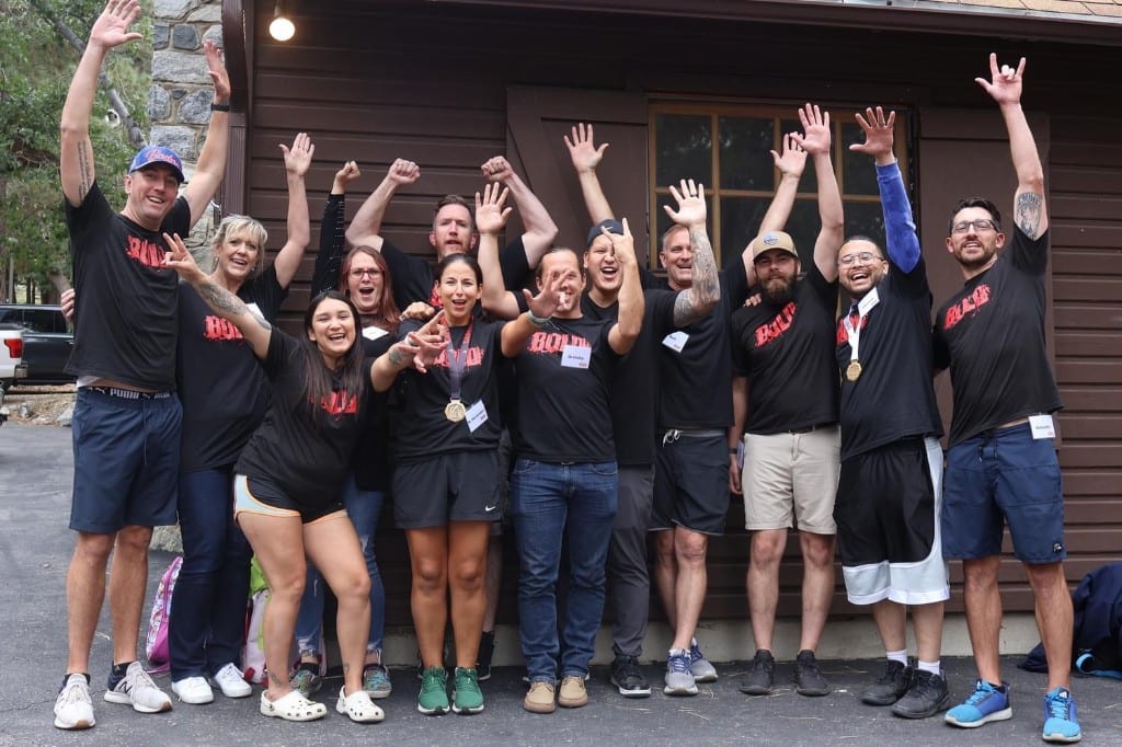 CI Web Group team cheering with arms raised outside the lodge at a BOLD Advanced Leadership session
