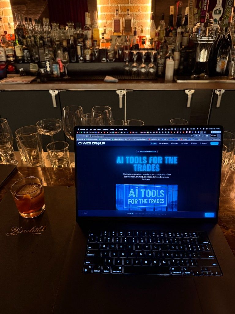 A laptop showing the AI Tools for the Trades site open on a bar top beside a cocktail