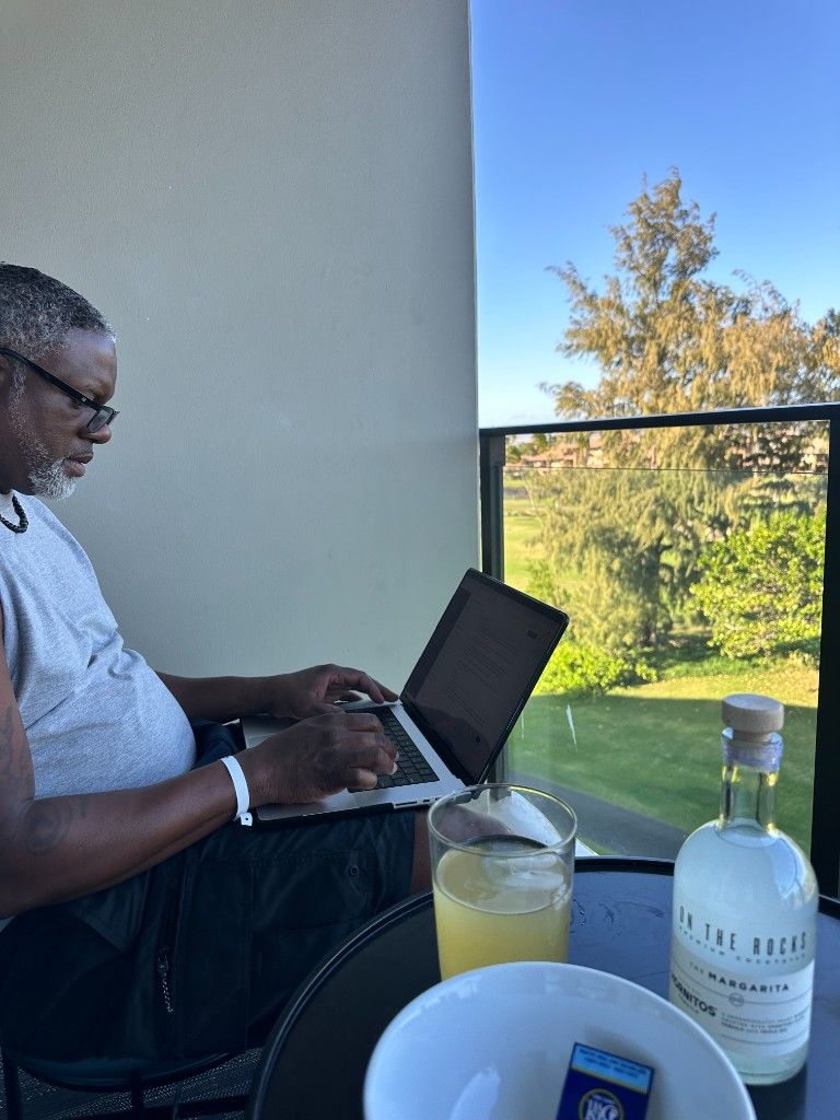 A CI Web Group team member working on a laptop on a balcony with greenery