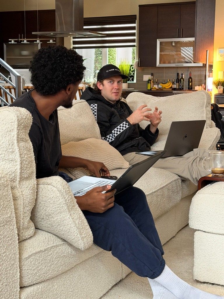 Two CI Web Group team members working on laptops on a couch