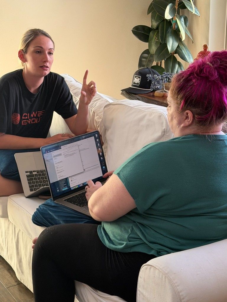 Two CI Web Group team members in a strategy session on a couch with laptops