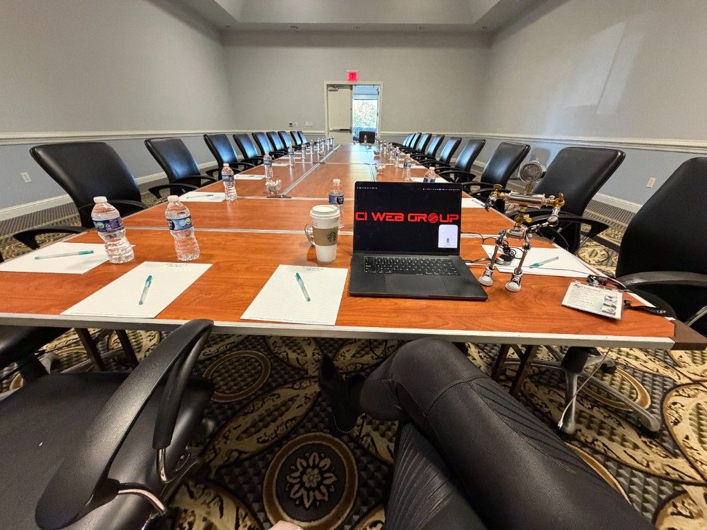 A boardroom set for a CI Web Group session with a branded laptop on the table