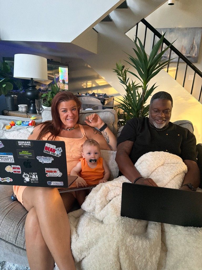 CI Web Group team members working on laptops on a couch with a baby