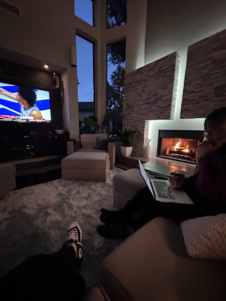 A CI Web Group team member working on a laptop by a fireplace in the evening