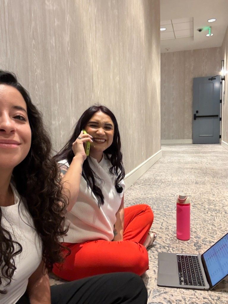 Two CI Web Group team members working from a hotel hallway, one on a call