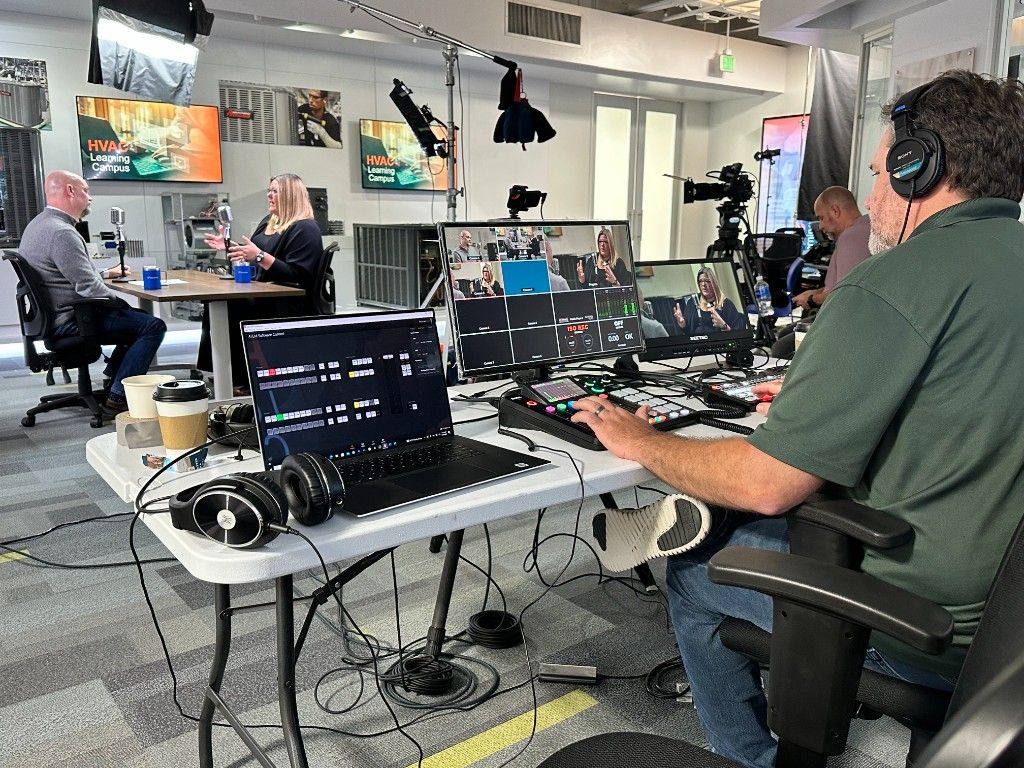A CI Web Group team member running a video production control desk with monitors and a switcher