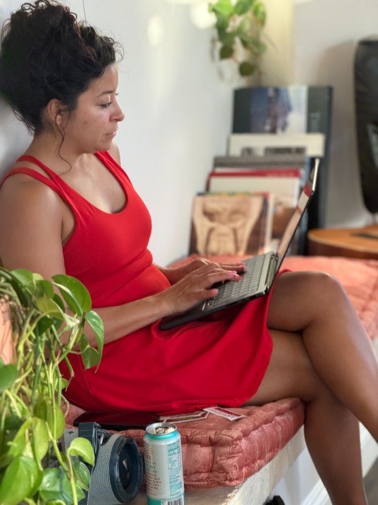 A CI Web Group team member working on a laptop on a couch beside a plant