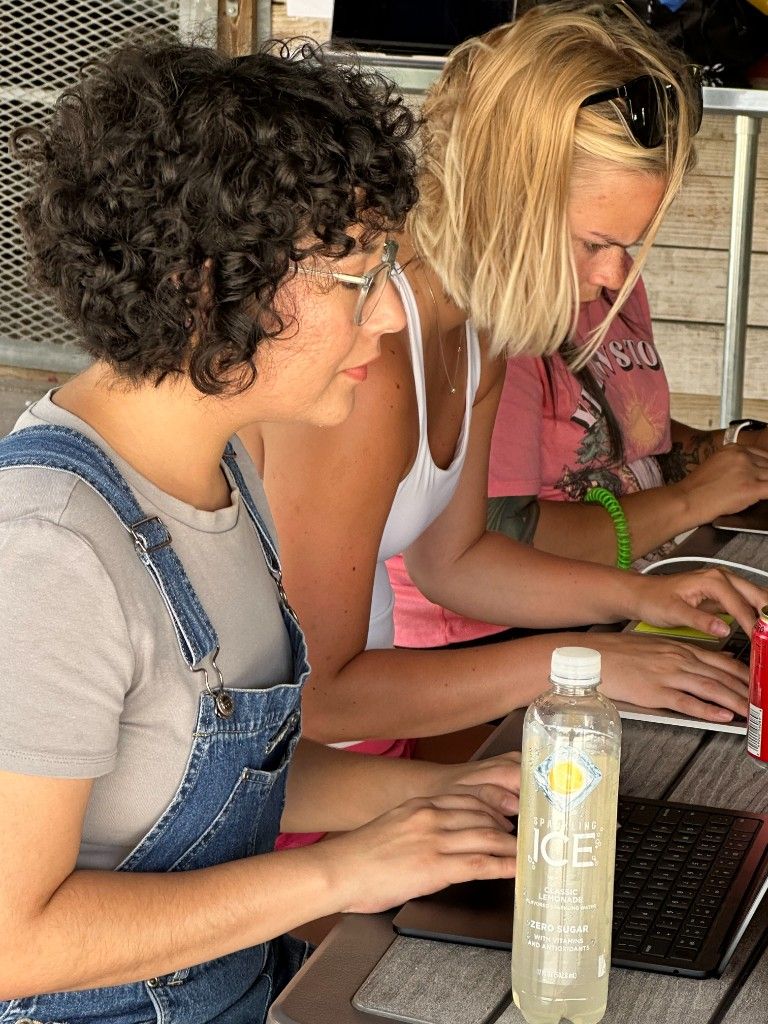 Two CI Web Group team members working closely side by side on laptops