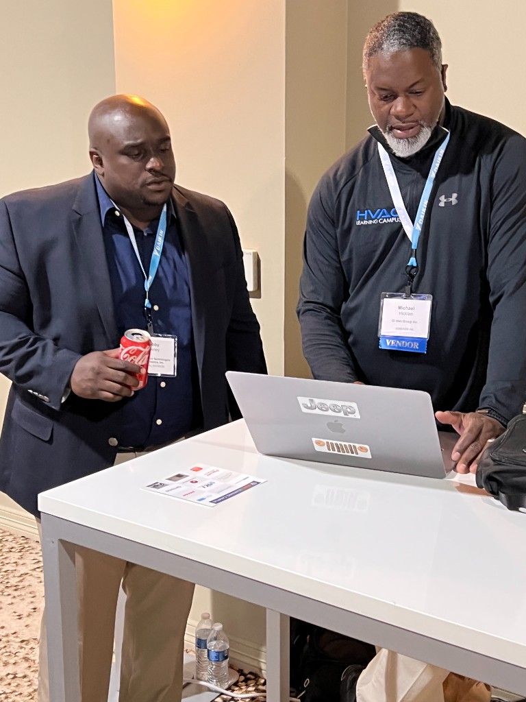 Two CI Web Group team members working at a standing table at an event