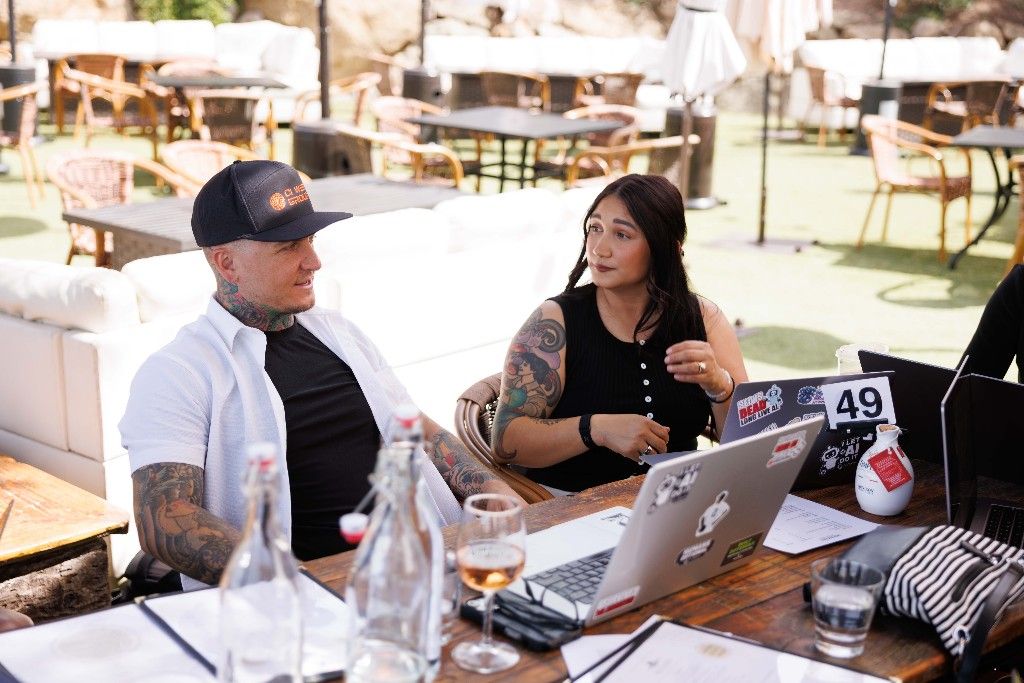 Two CI Web Group team members working on laptops at an outdoor lounge