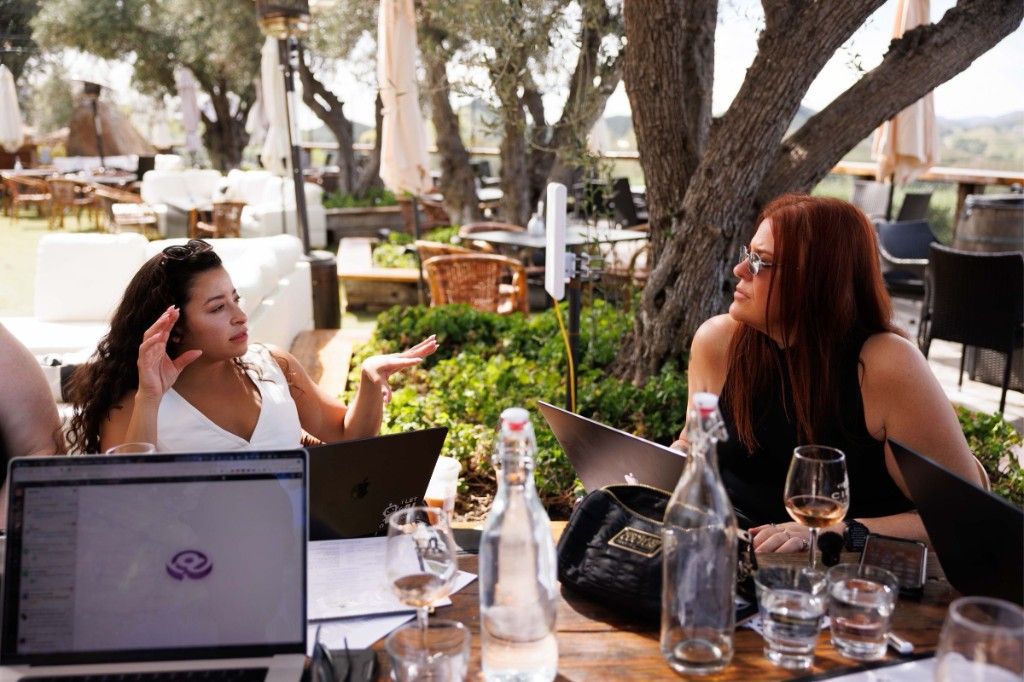 Two CI Web Group team members working on laptops at an outdoor vineyard table