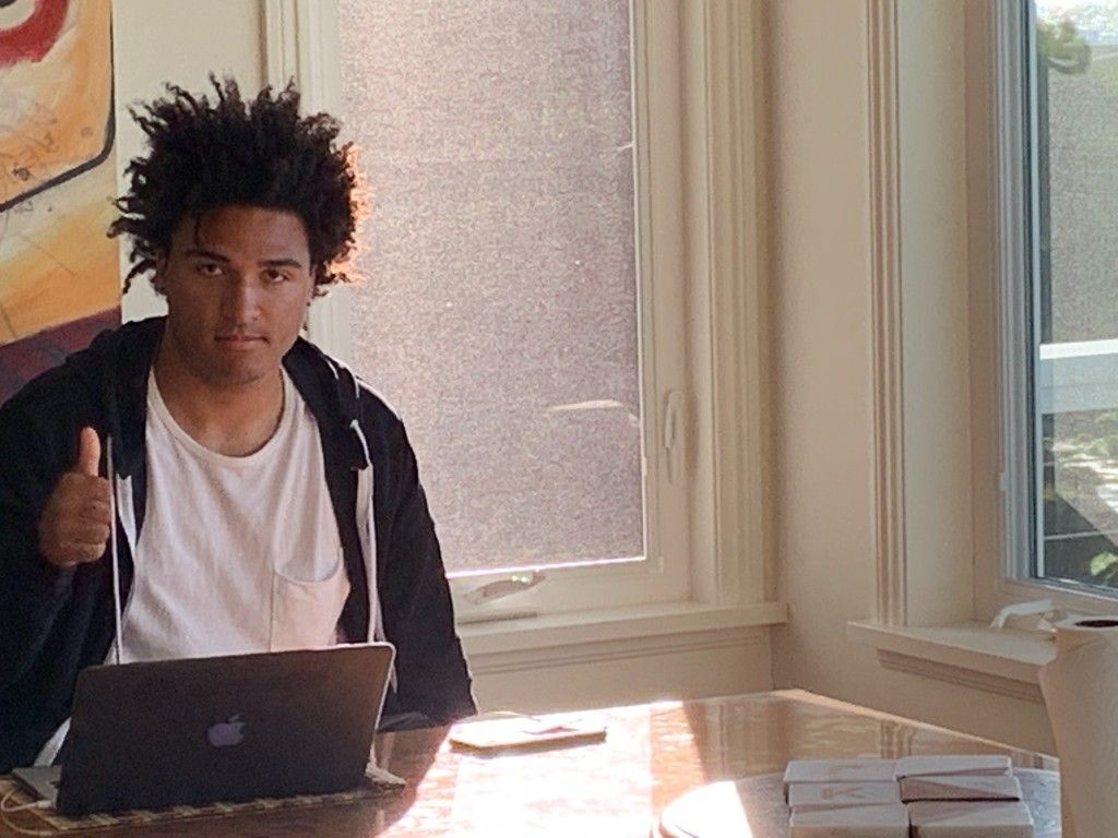 A CI Web Group team member giving a thumbs up at a laptop by a sunny window