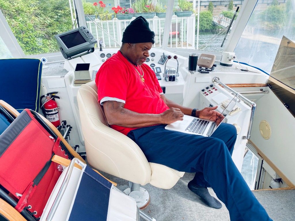 A CI Web Group team member working on a laptop at the helm of a boat