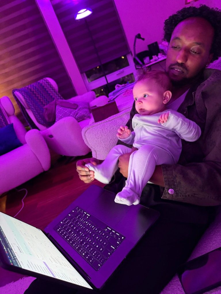 A CI Web Group team member working on a laptop while holding a baby