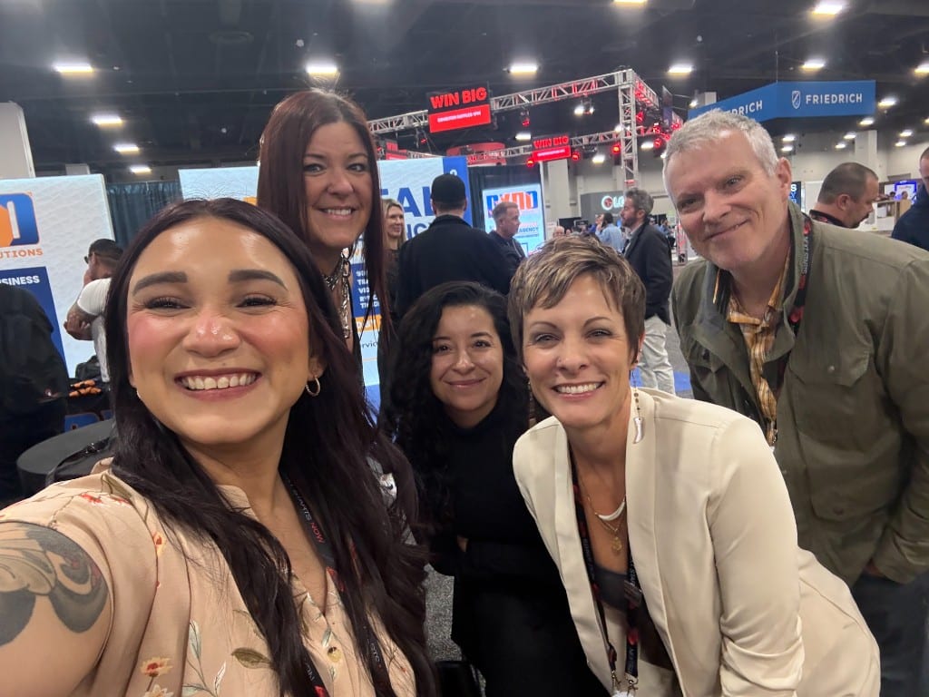 CI Web Group team and clients taking a selfie on an industry expo floor