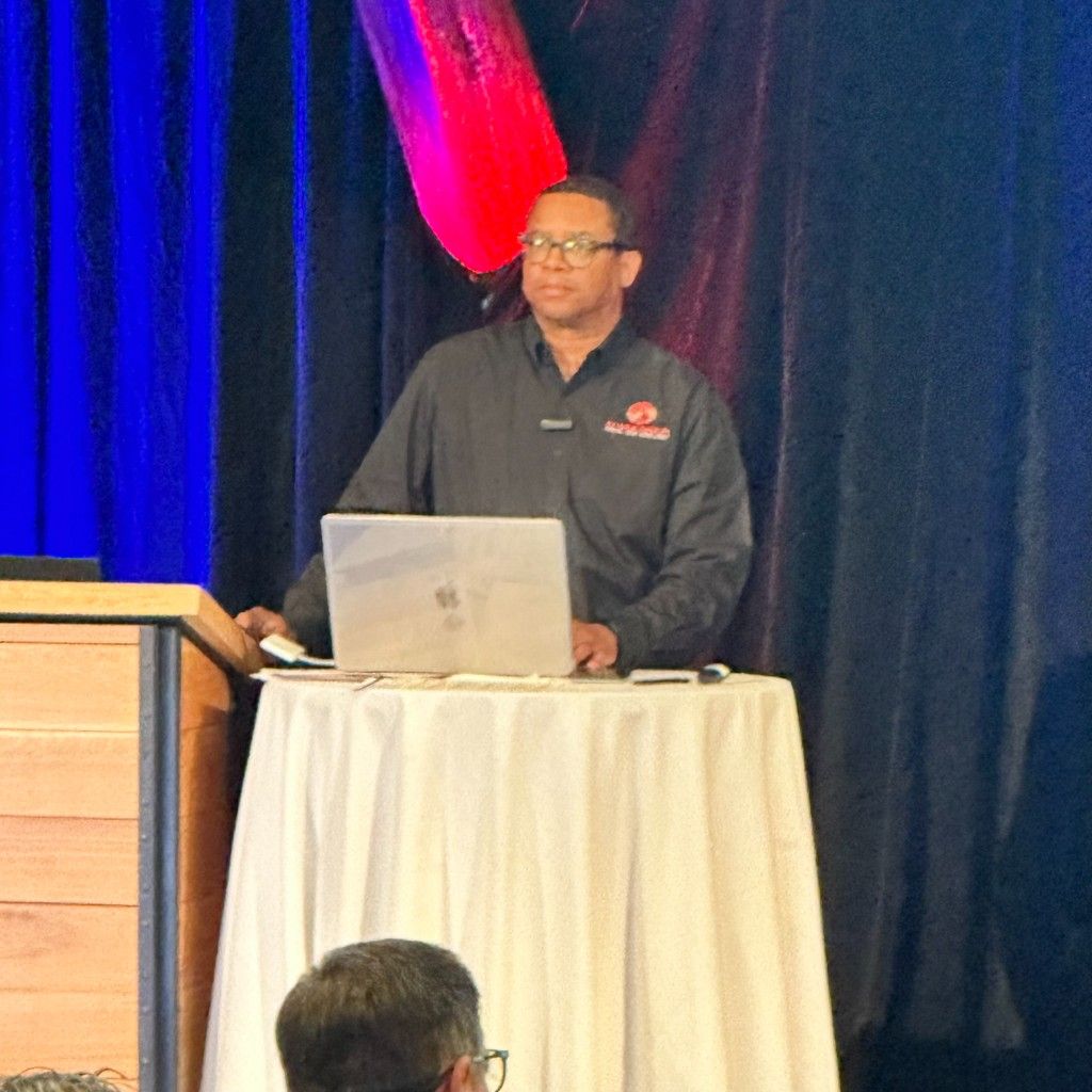 A CI Web Group speaker presenting from the podium to a trades-industry audience