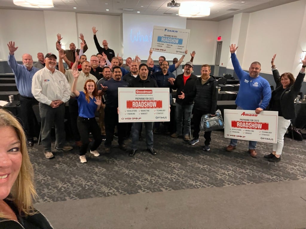 Contractors cheering with manufacturer roadshow signs at a CI Web Group training event