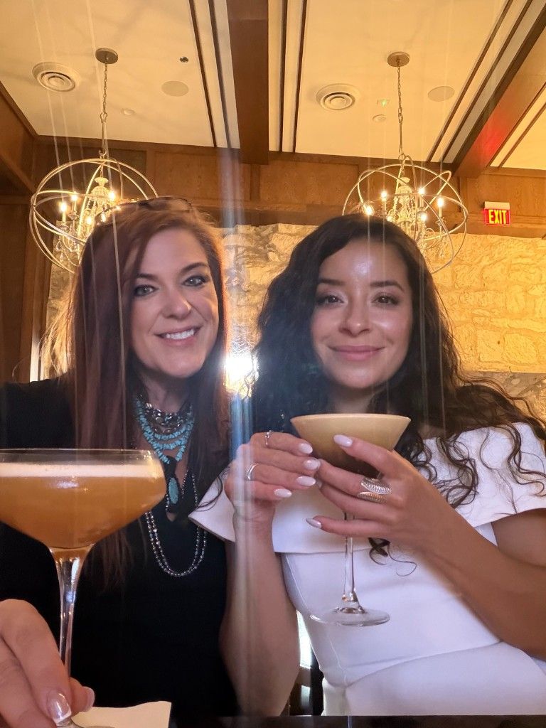 Two CI Web Group team members toasting cocktails at an evening event