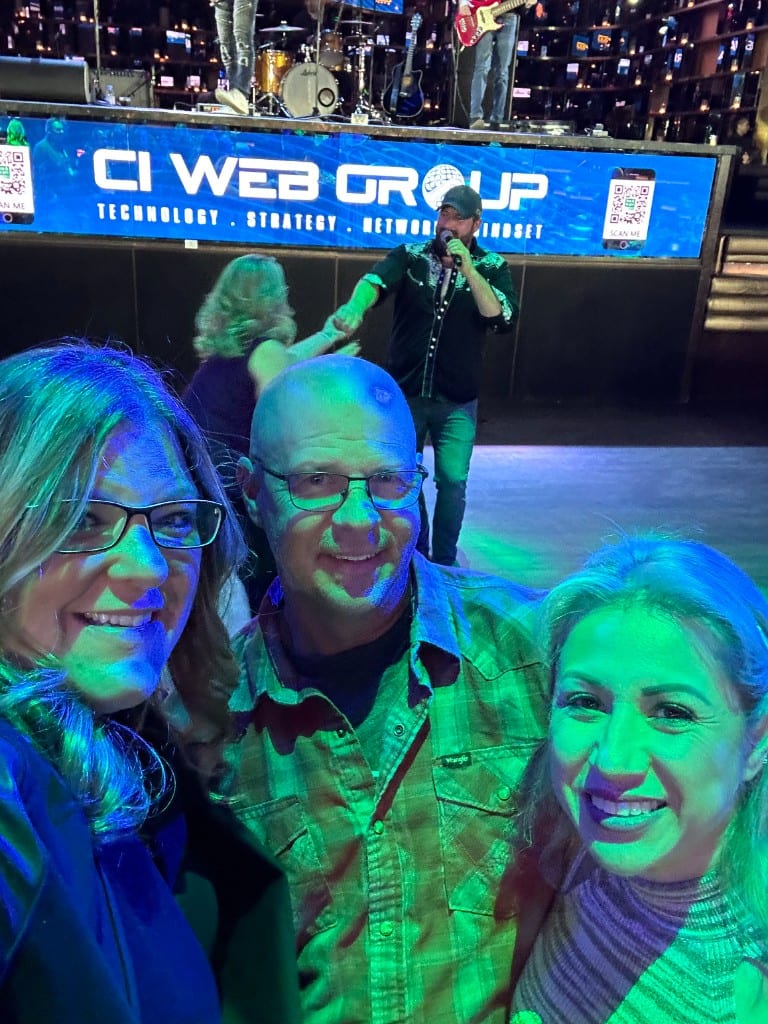 CI Web Group team members at an evening event under stage lights