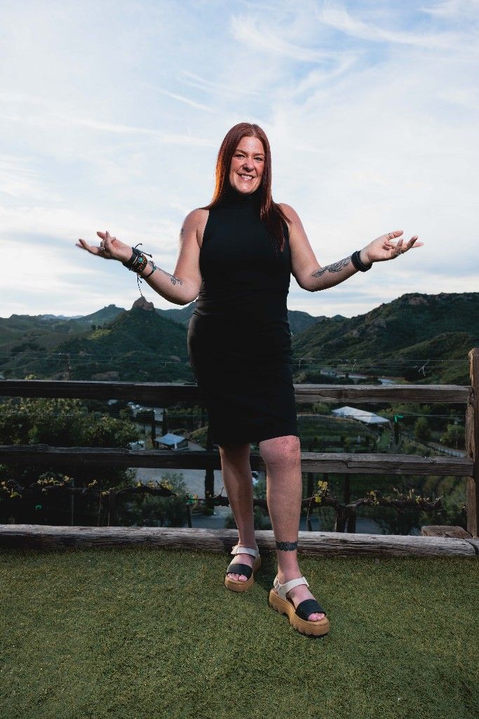 A CI Web Group team member with arms open on a hillside at a team retreat