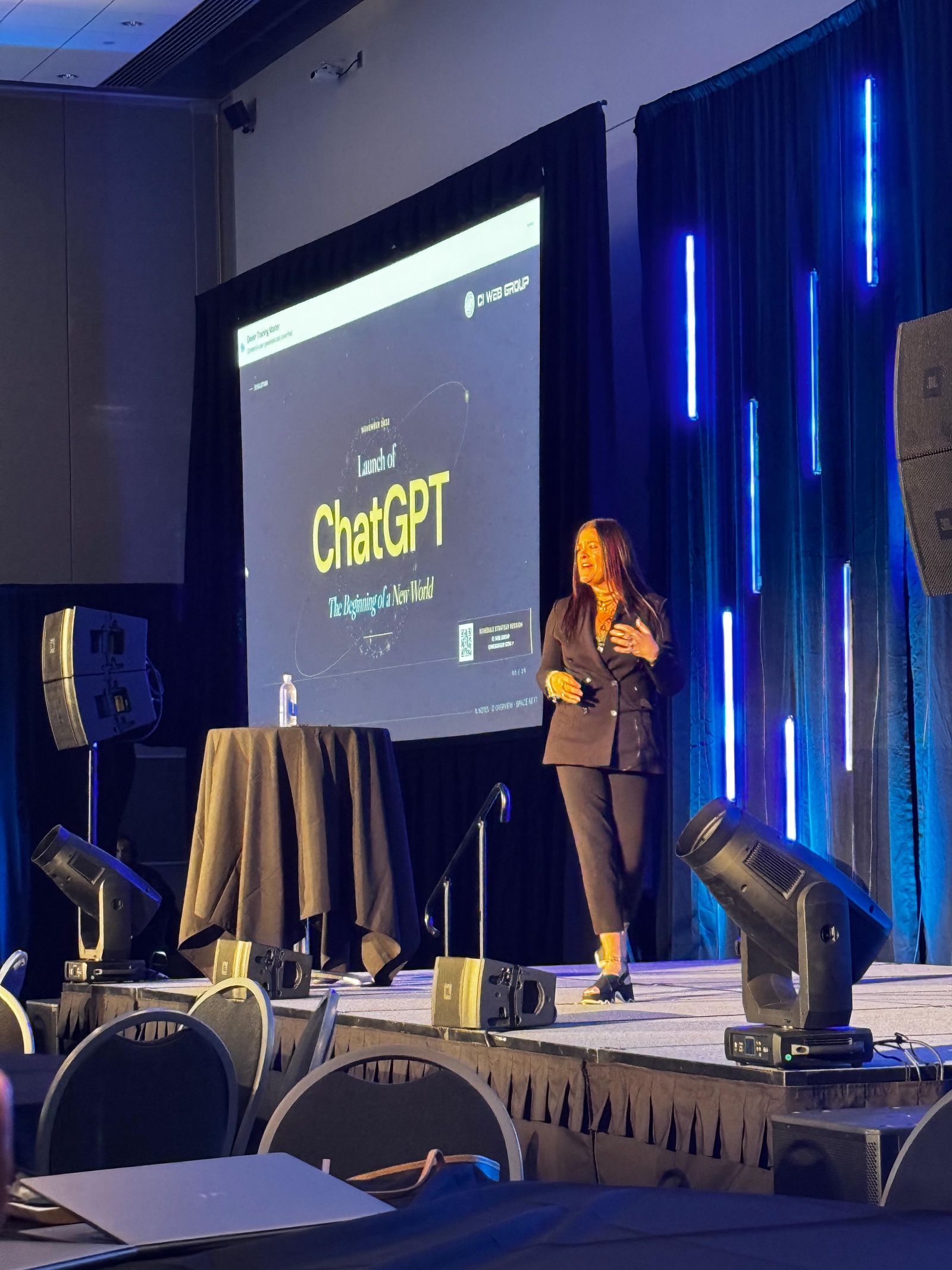 Jennifer Bagley speaking on stage in front of a slide about the launch of ChatGPT