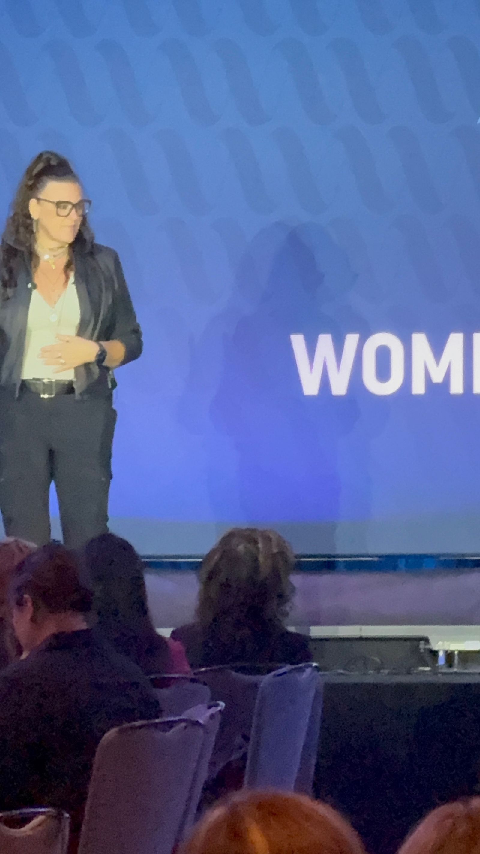 Jennifer Bagley speaking on stage at the Women in HVACR event, with the audience in the foreground