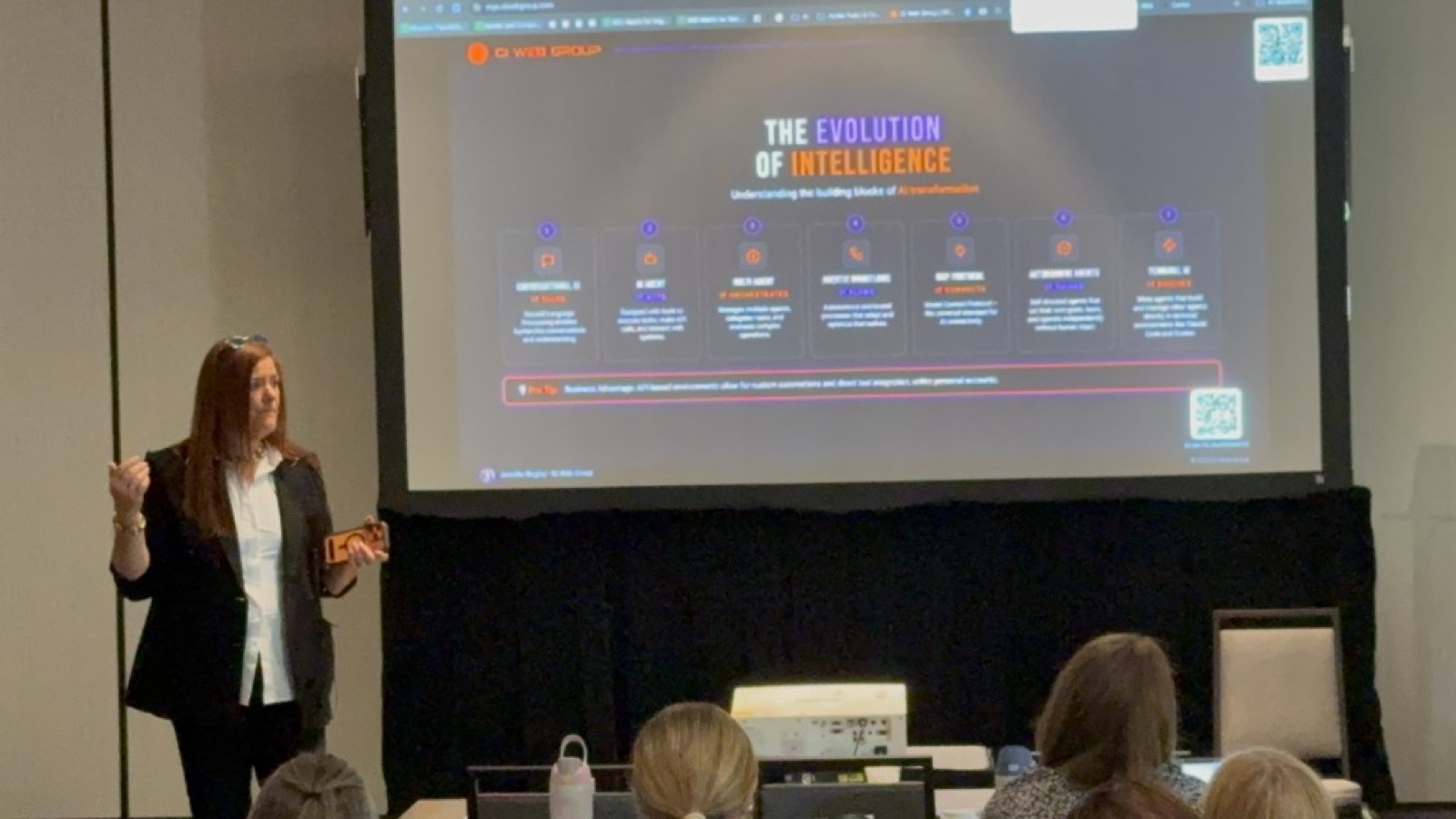 Jennifer Bagley of CI Web Group presenting 'The Evolution of Intelligence' AI keynote slide to a trades audience