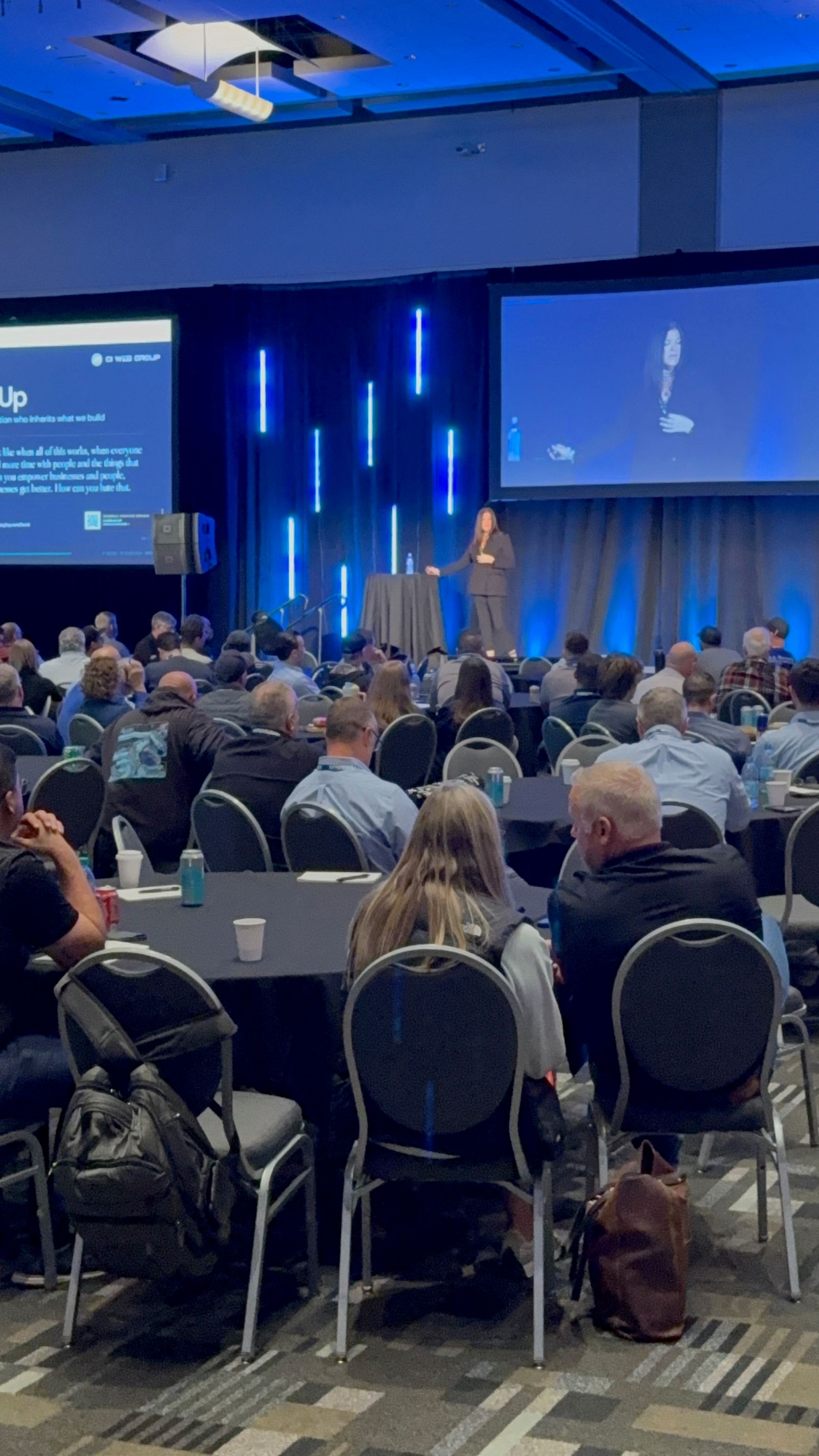 Jennifer Bagley presenting to a ballroom of trades professionals with a Hands Up book slide on screen