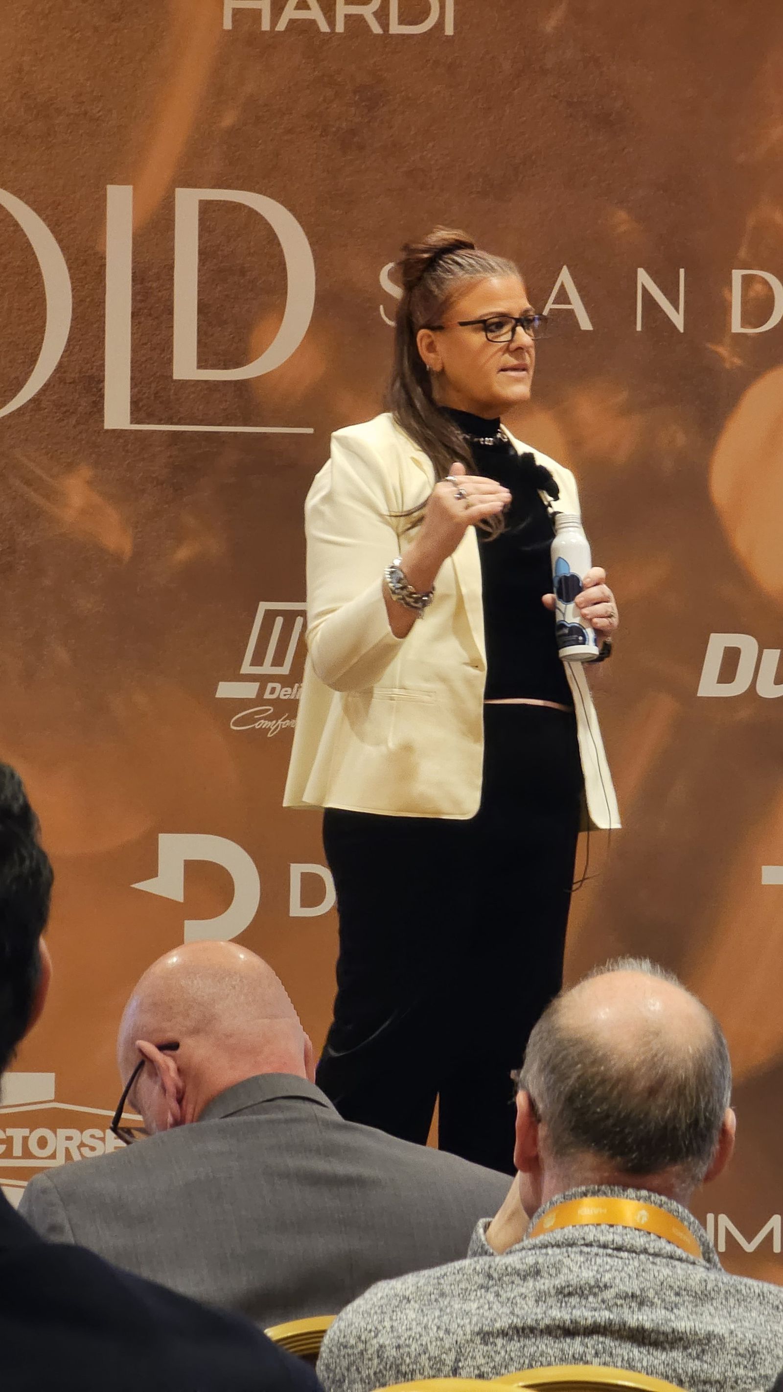 Close-up of Jennifer Bagley speaking in front of the HARDI Gold Standard backdrop
